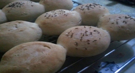 fresh baked buns with cumin lying on a grating, slightly connected to each other.