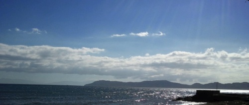 sunny day on the beach, a band of clouds in the distance and visible sunrays on the right upper corner